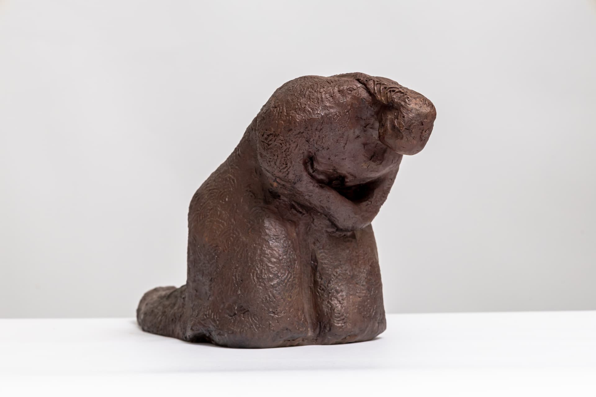 Grief, seated bronze figure hunched forward