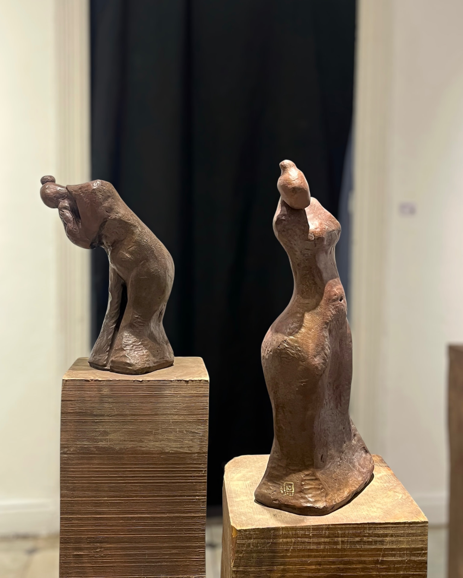 Two bronze figure studies side by side on wooden plinths