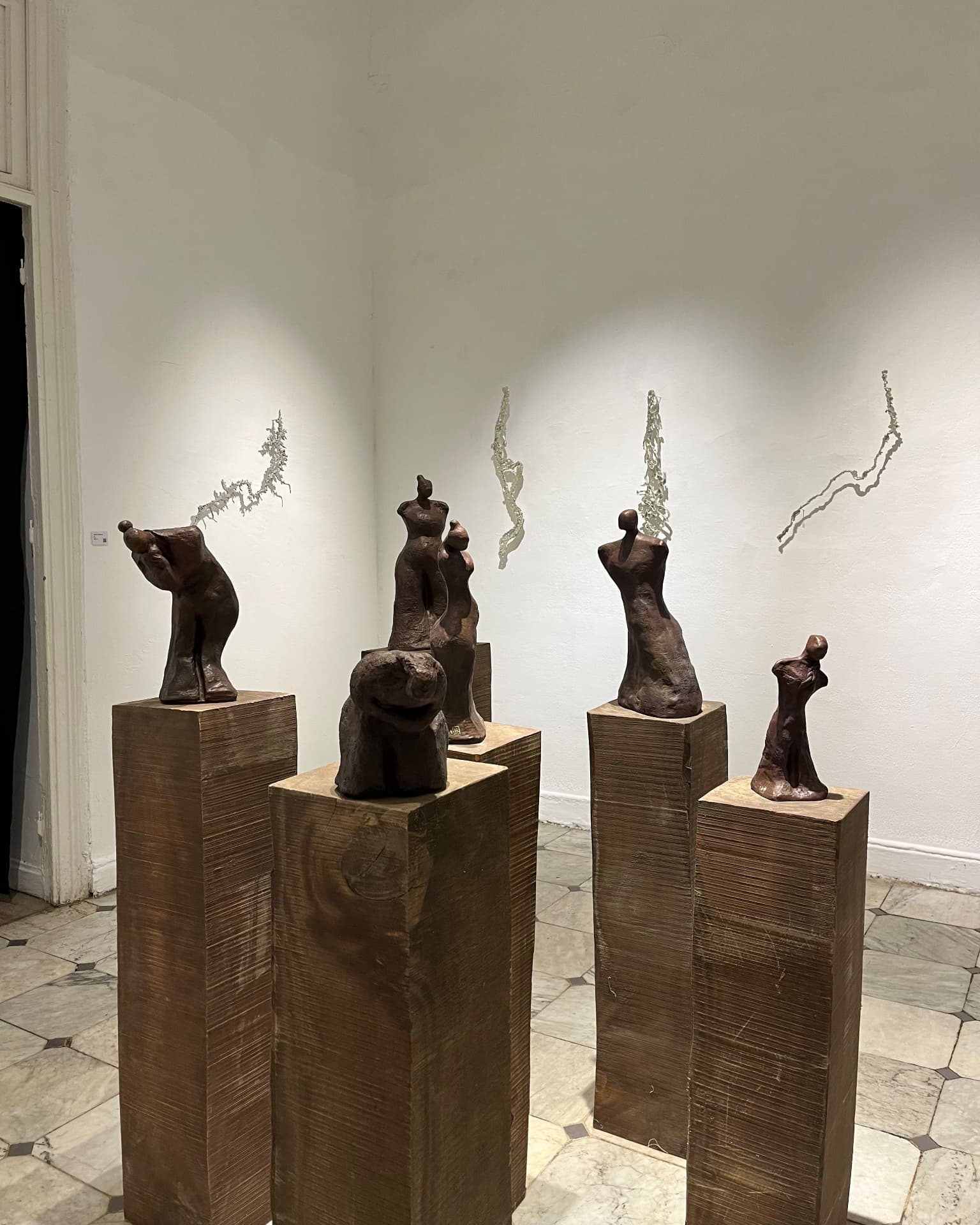 Bronze figure studies displayed in a white-walled room