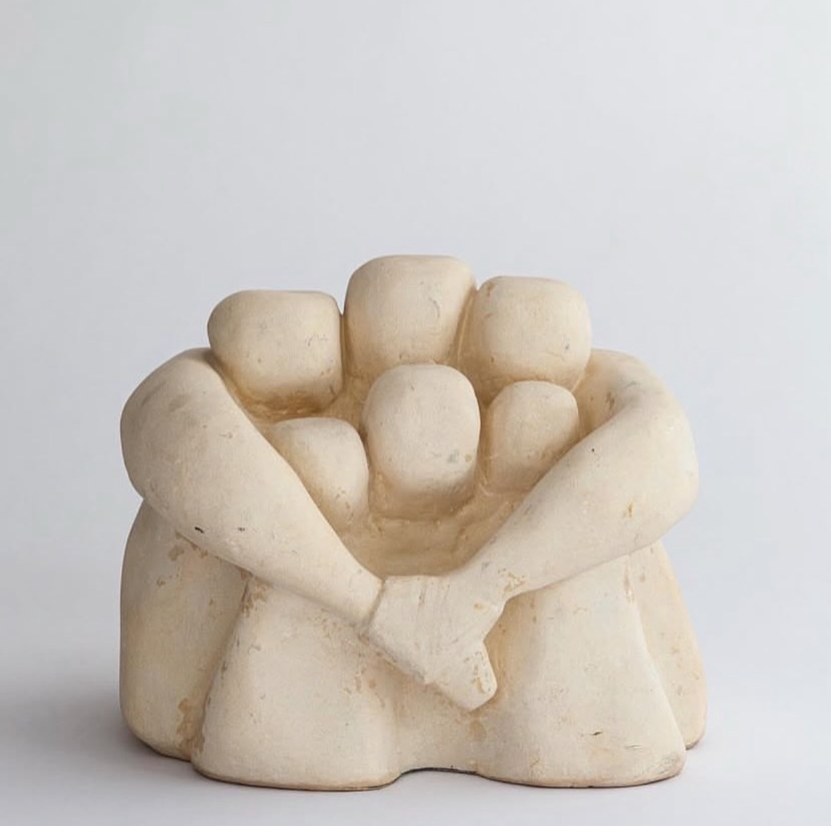 Pale plaster group of embracing figures cradling smaller forms