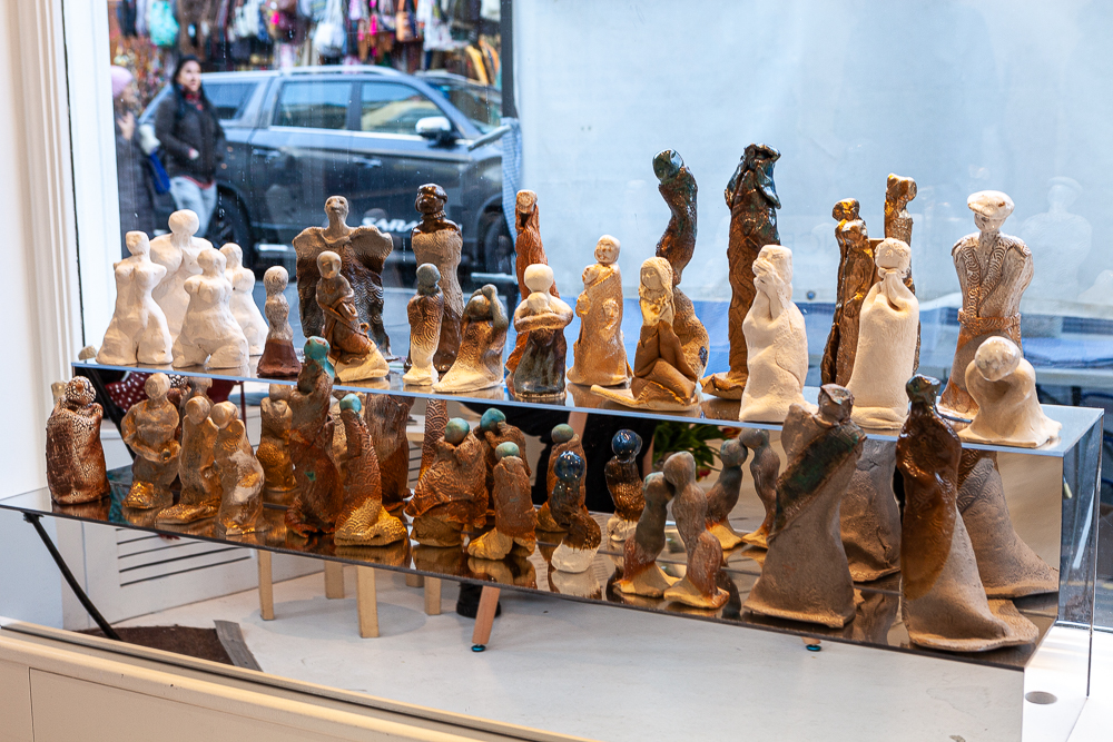 Display case filled with small glazed and sand-coloured ceramic figures